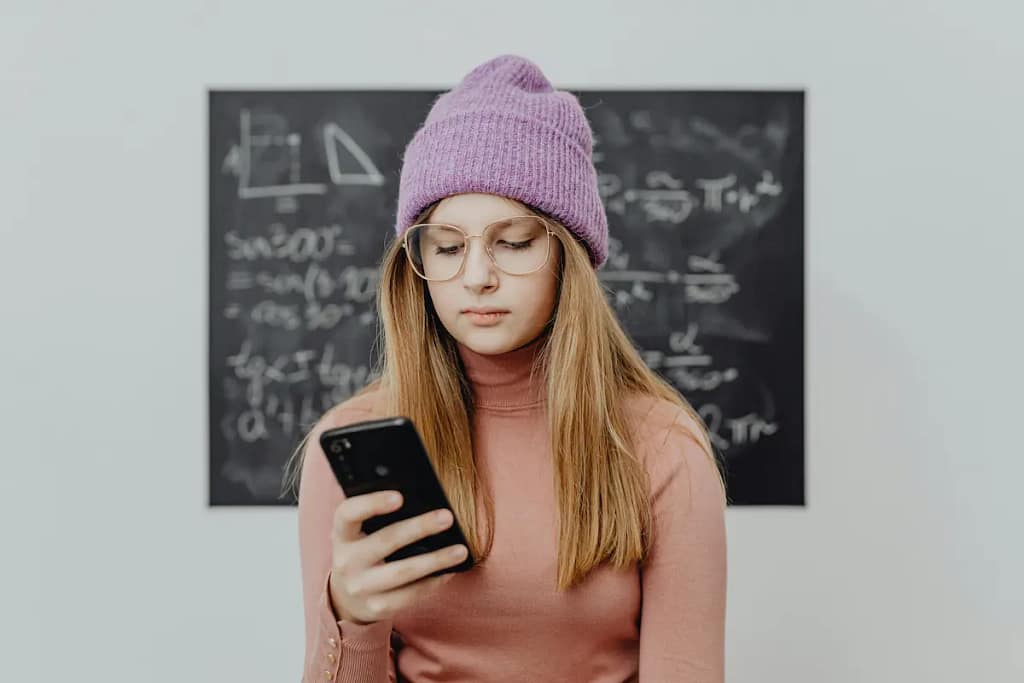 Adolescente a usar telemóvel, representando o impacto das redes sociais na saúde mental dos jovens