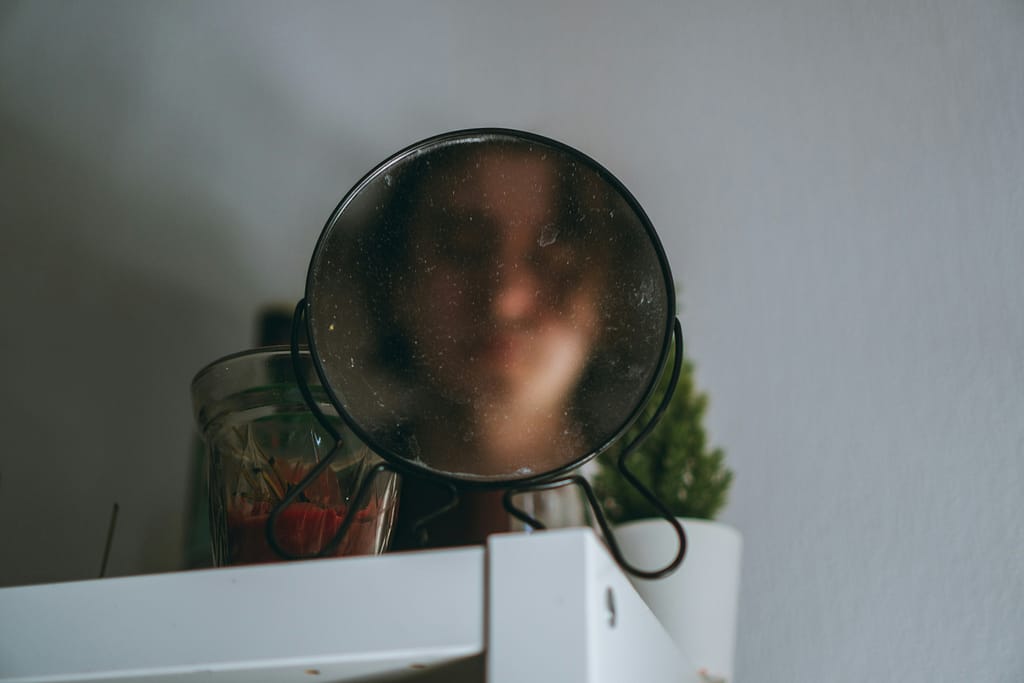 Adolescente a olhar-se ao espelho com imagem desfocada, representando insegurança com a imagem corporal na adolescência