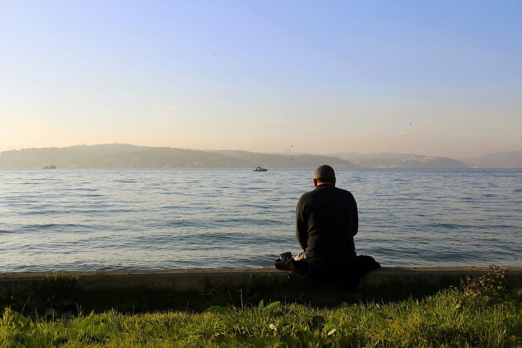 homem a olhar para o mar em momento de reflexão e contacto interno reflectindo não consigo relaxar
