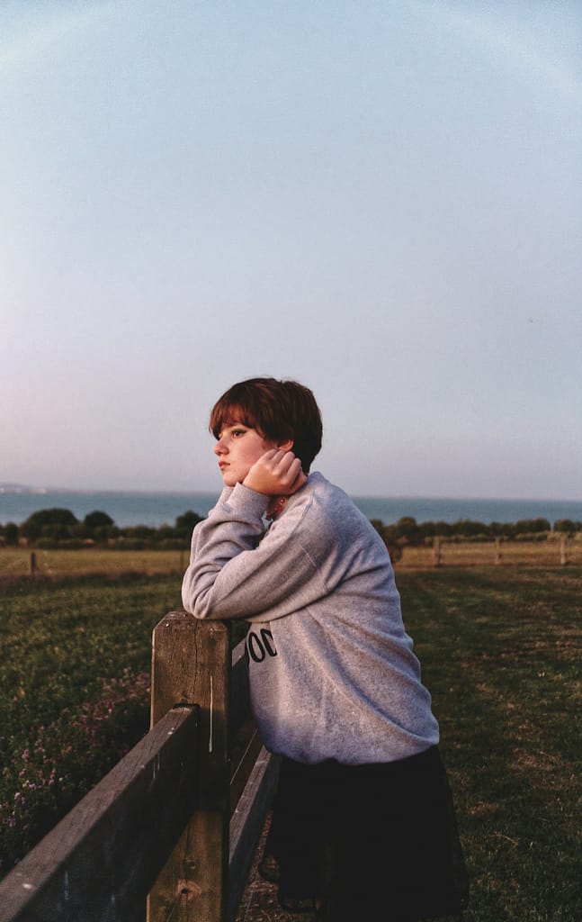 Adolescente encostada a uma vedação, num momento de recolhimento ao fim do dia representando tristeza e mal-estar emocional na adolescência