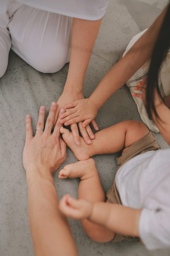 Mãos de pais e criança juntas, representando vínculo acompanhamento parental e apoio familiar