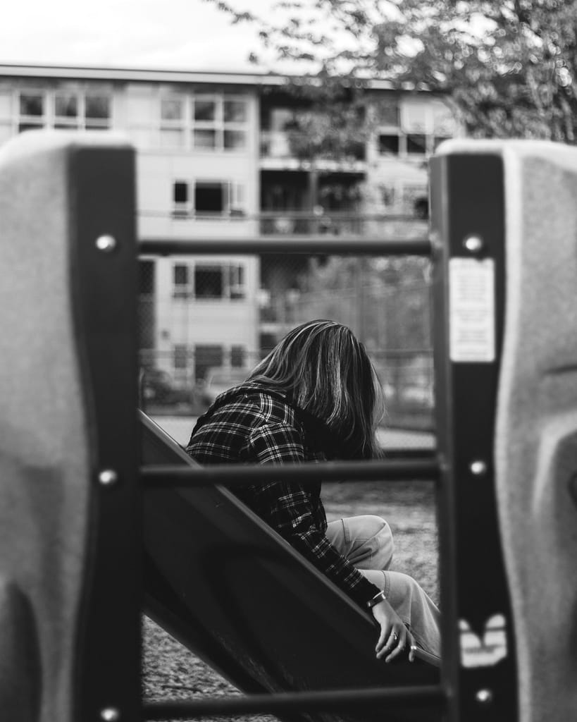 Adolescente sozinha em contexto escolar, ilustrando sentimento de exclusão e isolamento, ilustrando quando o adolescente se sente de fora do grupo